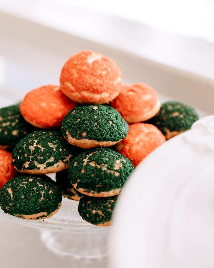 Choux cu craquelin verde și portocaliu, așezate pe platou