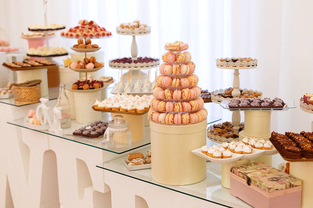 Masă dulce de eveniment, cu turn de macarons și prăjituri mici pe suporturi
