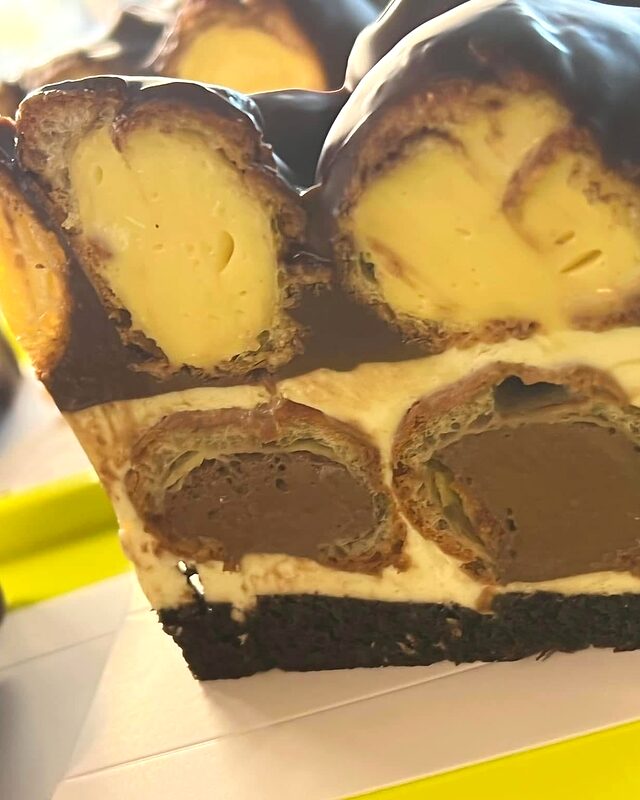 Secțiune de tort cu choux umplute cu vanilie, în glazură de ciocolată