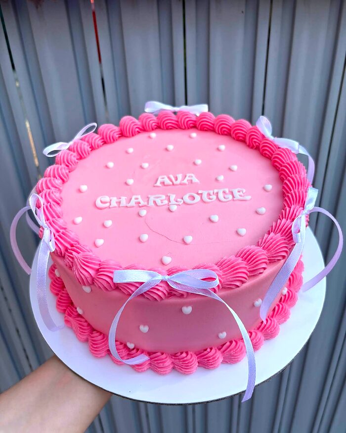 Tort roz cu buttercream și perle albe, cu numele scris deasupra