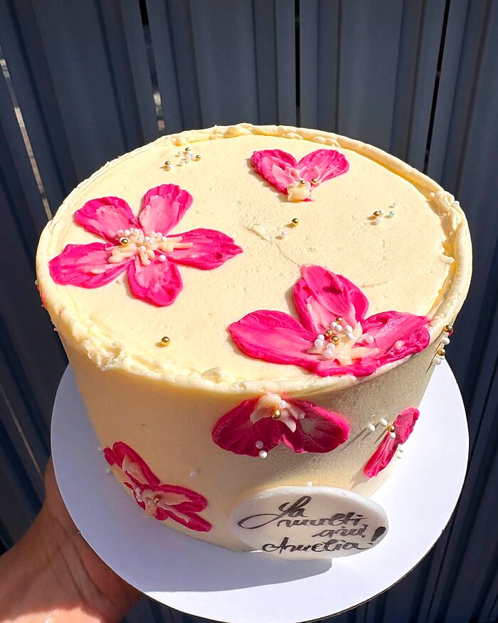 Tort crem cu flori roz proaspete pe margine