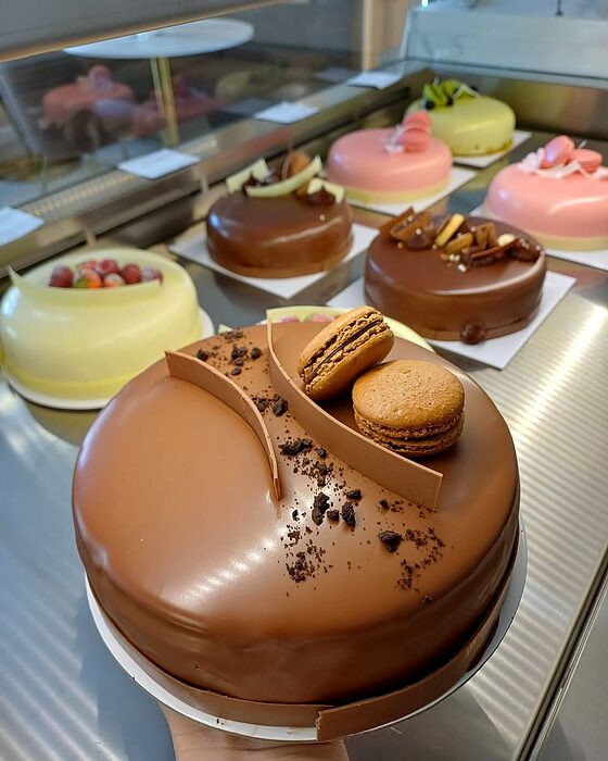 Vitrina cofetăriei Lulu, cu un entremet de ciocolată și prăjituri cu macarons