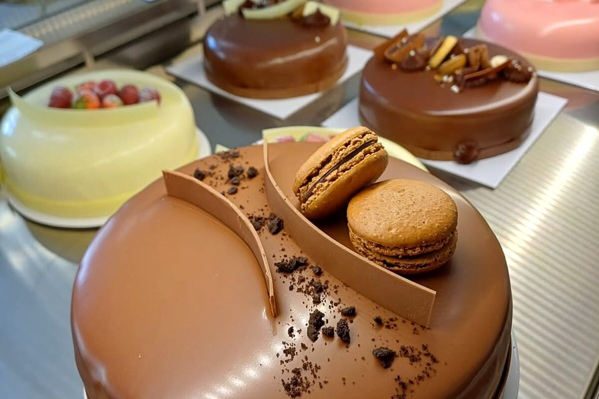 Vitrina cofetăriei Lulu, cu un tort de ciocolată și prăjituri cu macarons